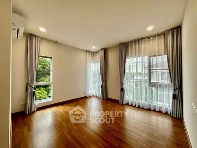Spacious corner unit with large windows and elegant curtains, featuring beautiful hardwood floors and abundant natural light.