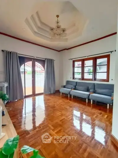 Spacious living room with elegant chandelier and polished wooden floors