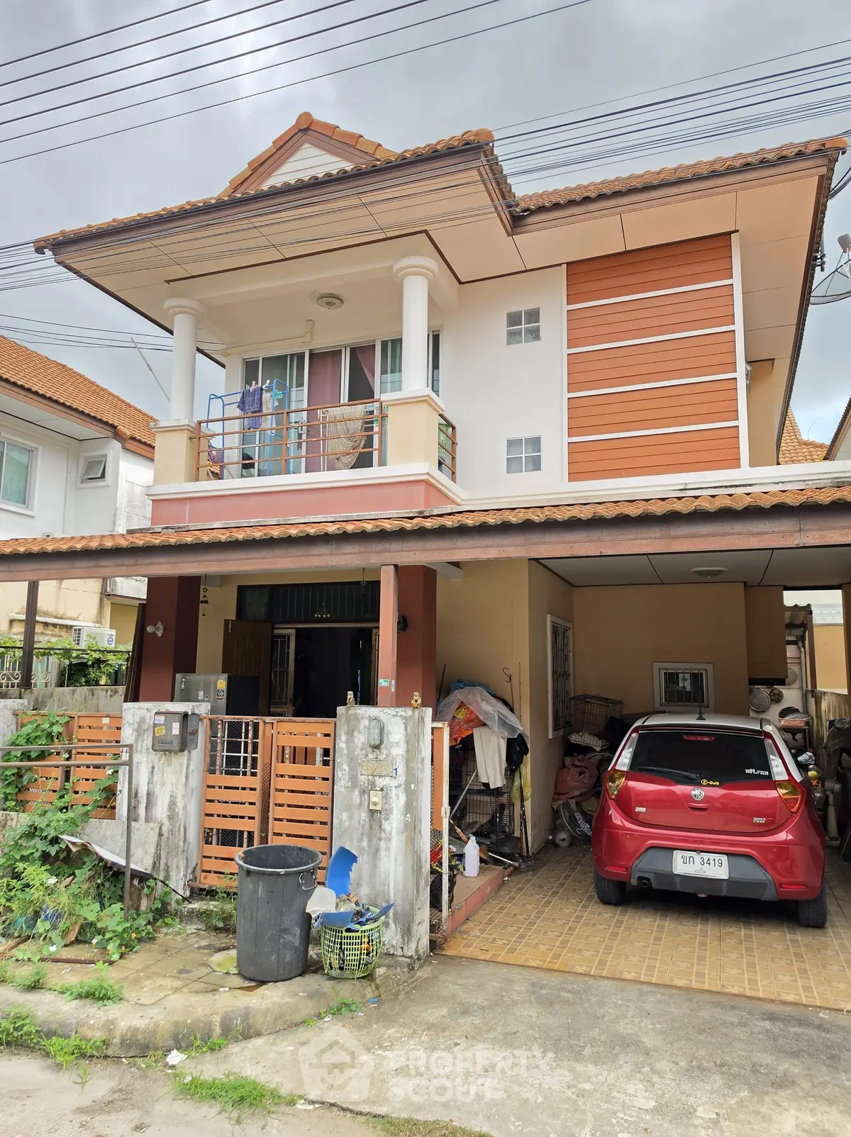 Charming two-story house with balcony and carport in a suburban neighborhood.