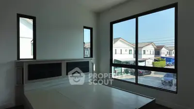Spacious bedroom with large windows offering a serene neighborhood view, perfect for natural light lovers.