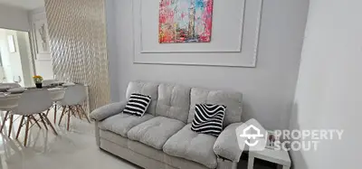 Modern living room with stylish decor and dining area, featuring a comfortable sofa and elegant wall art.