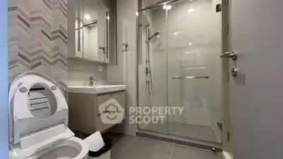 Modern bathroom with glass shower and sleek fixtures in contemporary apartment.