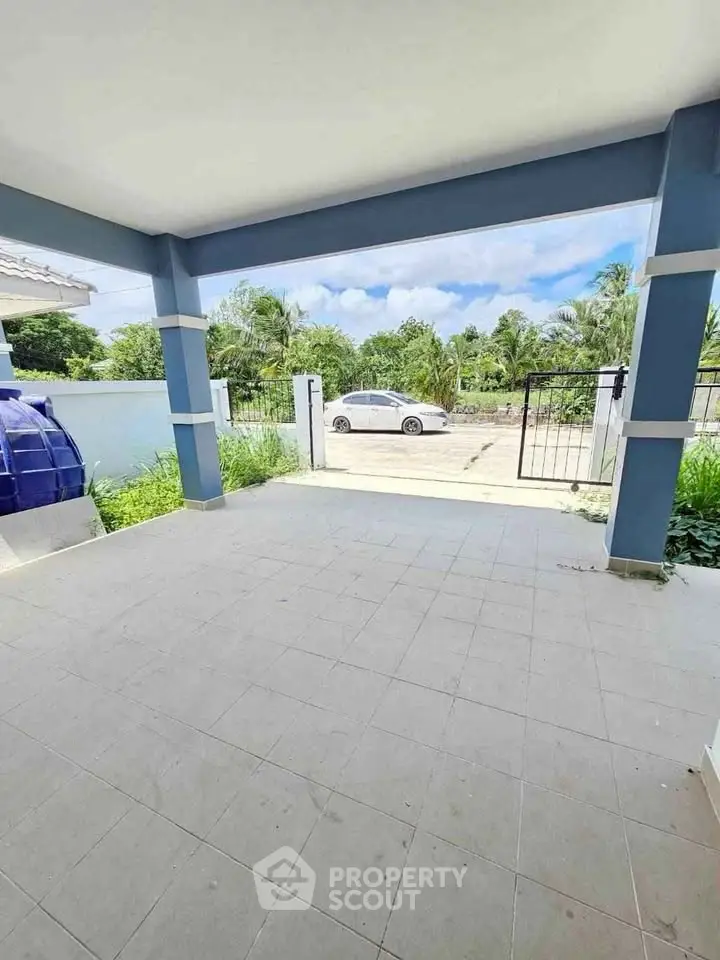 Spacious covered patio with tiled flooring and garden view, perfect for outdoor relaxation.