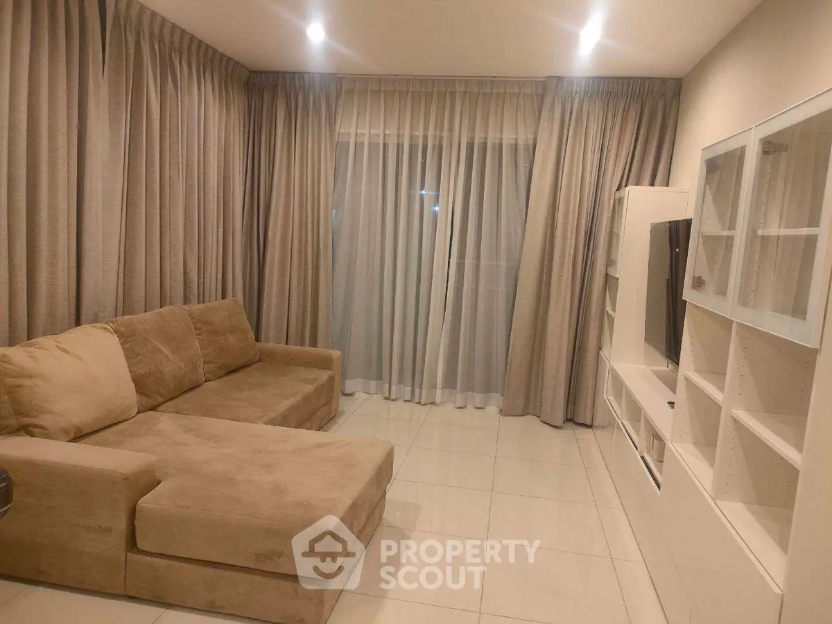 Spacious living room with modern beige sofa and elegant curtains