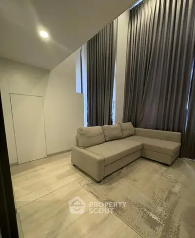 Modern living room with high ceilings and elegant curtains, featuring a cozy beige sectional sofa.