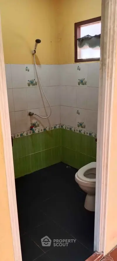 Cozy bathroom with shower and toilet, featuring vibrant green and white tiles.