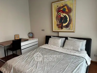 Modern bedroom with stylish decor and cozy bedding, featuring a sleek desk and contemporary artwork.