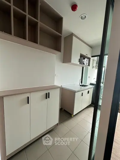 Modern kitchen with sleek cabinetry and tiled flooring in a contemporary apartment.