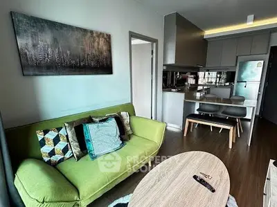 Modern living room with green sofa and open kitchen layout in stylish apartment.