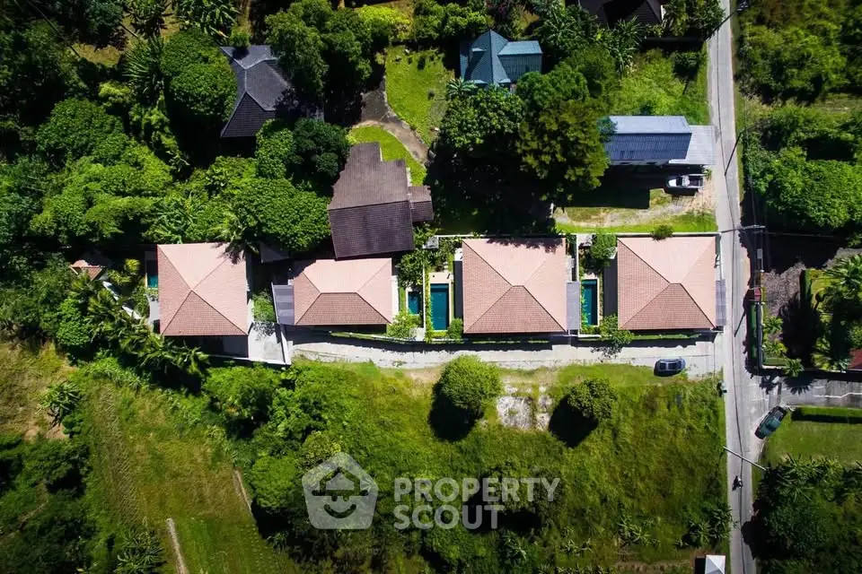 Aerial view of modern villas with private pools surrounded by lush greenery.