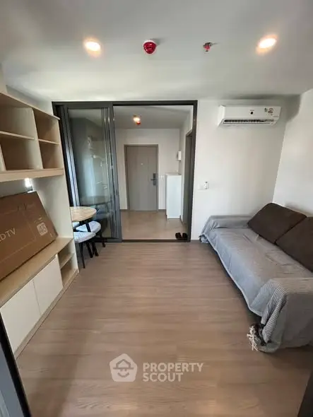Modern living room with sleek design and air conditioning, featuring a cozy sofa and built-in shelving.