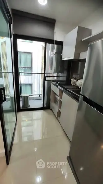 Modern kitchen with sleek appliances and balcony view in urban apartment