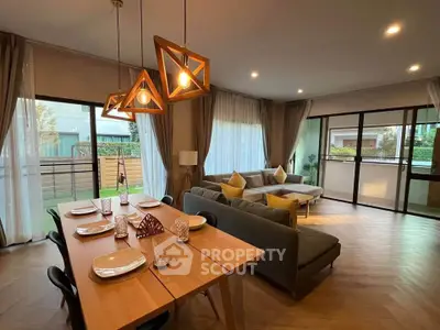 Spacious modern living room with stylish lighting and large windows offering garden views.