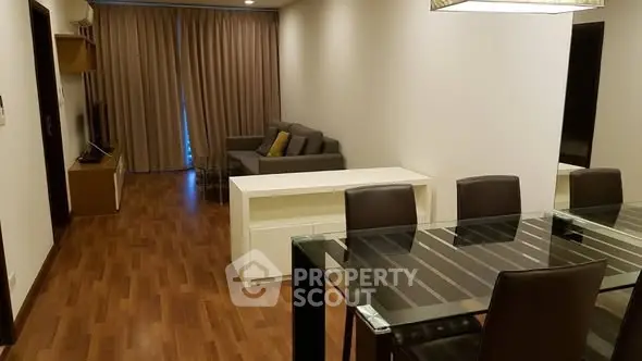 Spacious modern living room with glass dining table and cozy seating area.