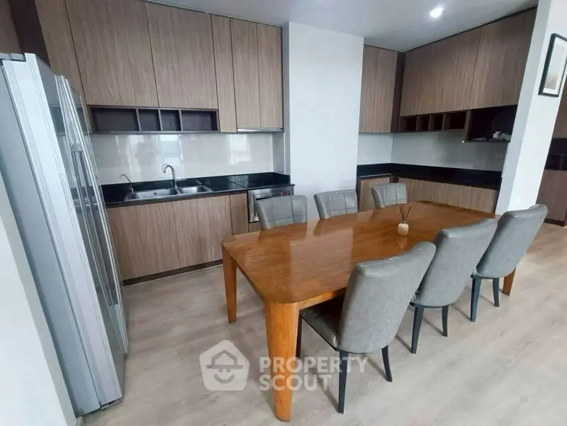 Modern kitchen with wooden cabinets and dining area, featuring sleek design and ample space.