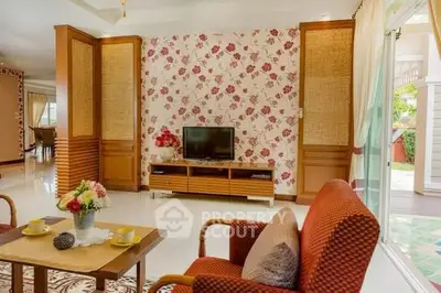 Charming living room with floral wallpaper and cozy seating area, perfect for relaxation.