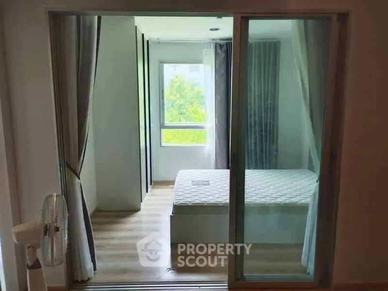 Modern bedroom with large window and sliding glass door, featuring a minimalist design.