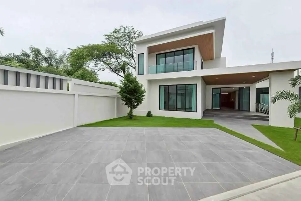 Modern luxury home with spacious driveway and lush greenery, perfect for upscale living.