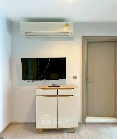 Modern interior with wall-mounted TV and air conditioner above sleek cabinet