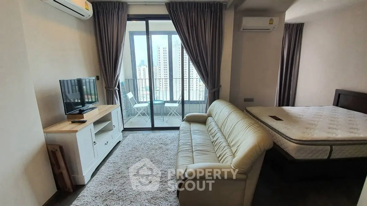 Modern studio apartment with balcony and city view, featuring cozy living area and comfortable bed.