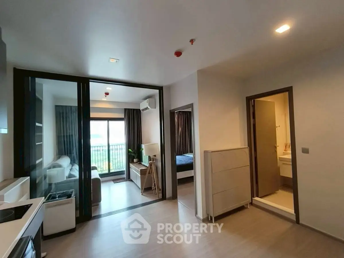 Modern apartment interior with open layout, featuring living room, bedroom, and kitchen area.