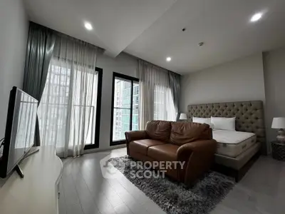 Modern studio apartment with stylish furniture and large windows offering city views.