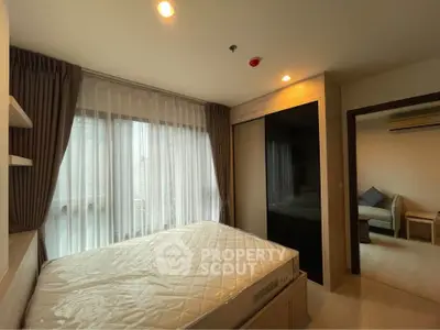Cozy bedroom with large window and modern furnishings in a stylish apartment.