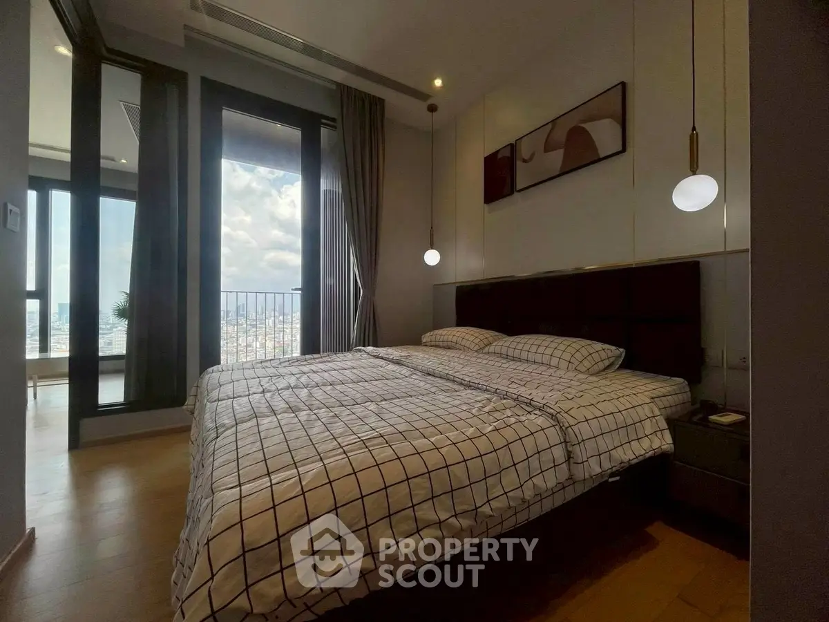 Modern bedroom with large windows and city view, featuring stylish decor and cozy bedding.