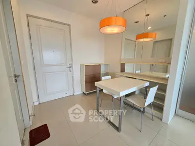 Modern dining area with sleek white table and chairs, accented by stylish pendant lighting.