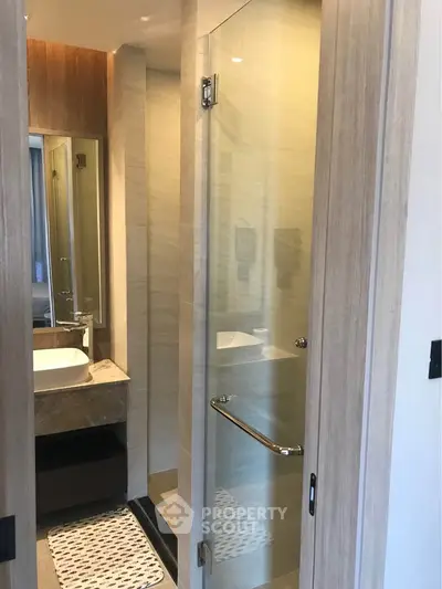 Modern bathroom with glass shower door and stylish vanity in a contemporary apartment.
