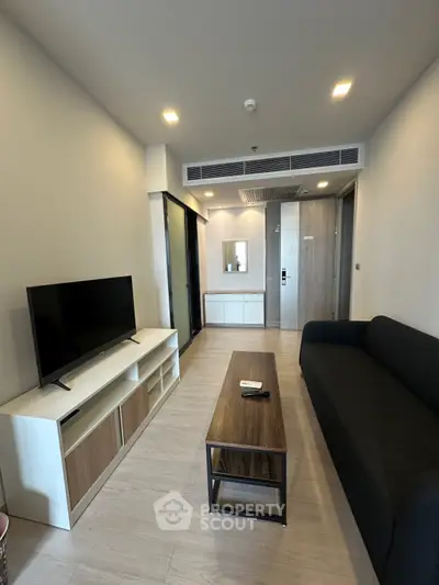 Modern living room with sleek furniture and flat-screen TV in a stylish apartment.
