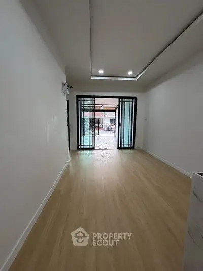 Spacious living room with wooden flooring and sliding glass doors leading to outdoor area.