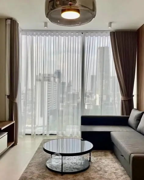 Modern living room with city view, featuring a sleek gray sofa and round coffee table.