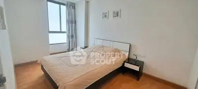 Spacious bedroom with large window and modern decor in a cozy apartment.