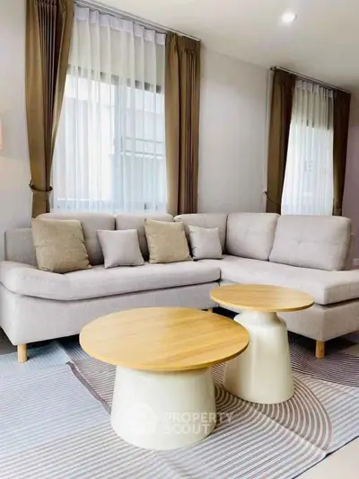 Modern living room with stylish beige sofa and round wooden coffee tables.