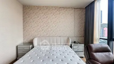 Spacious bedroom with elegant wallpaper and large windows offering city views.