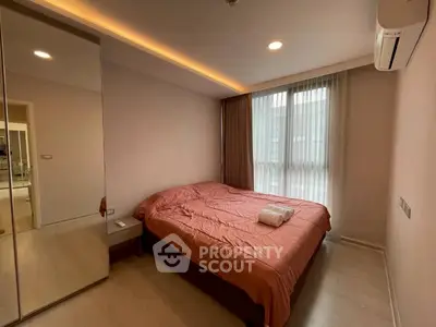 Cozy bedroom with modern design, featuring a large mirror and natural light.