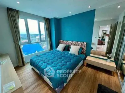 Modern bedroom with blue accent wall and large window offering city views.