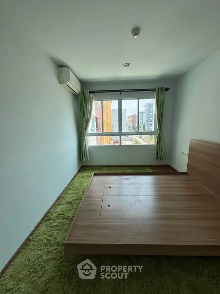 Spacious bedroom with large window and modern wooden bed frame, offering city views and natural light.