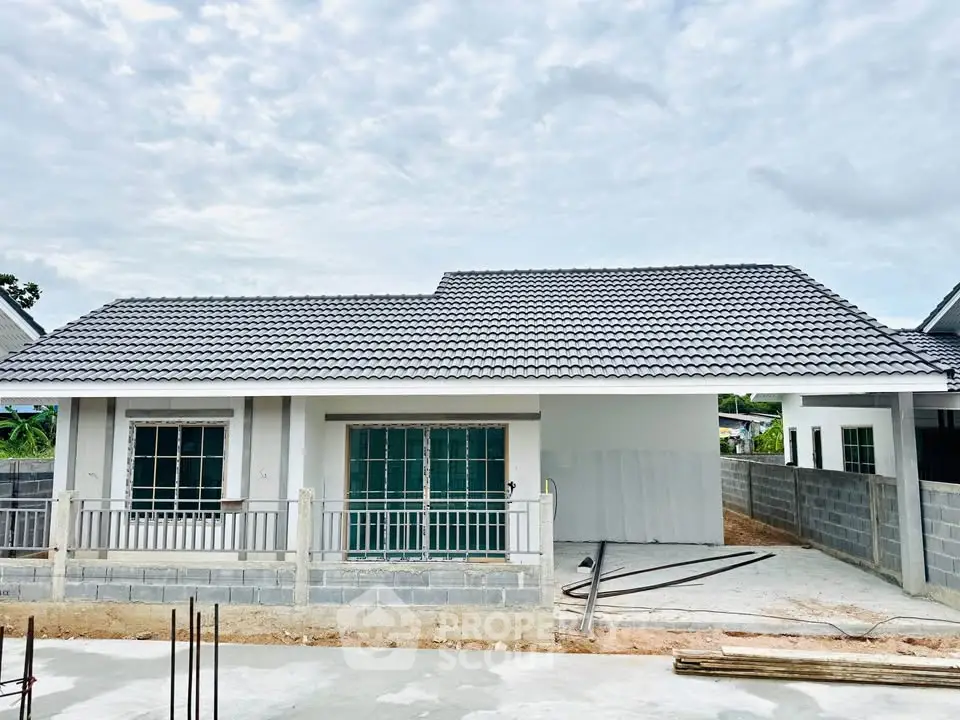 Charming single-story house with tiled roof and spacious driveway under a cloudy sky.