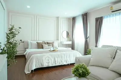 Luxurious bedroom with elegant decor and natural light, featuring cozy seating area and stylish furnishings.