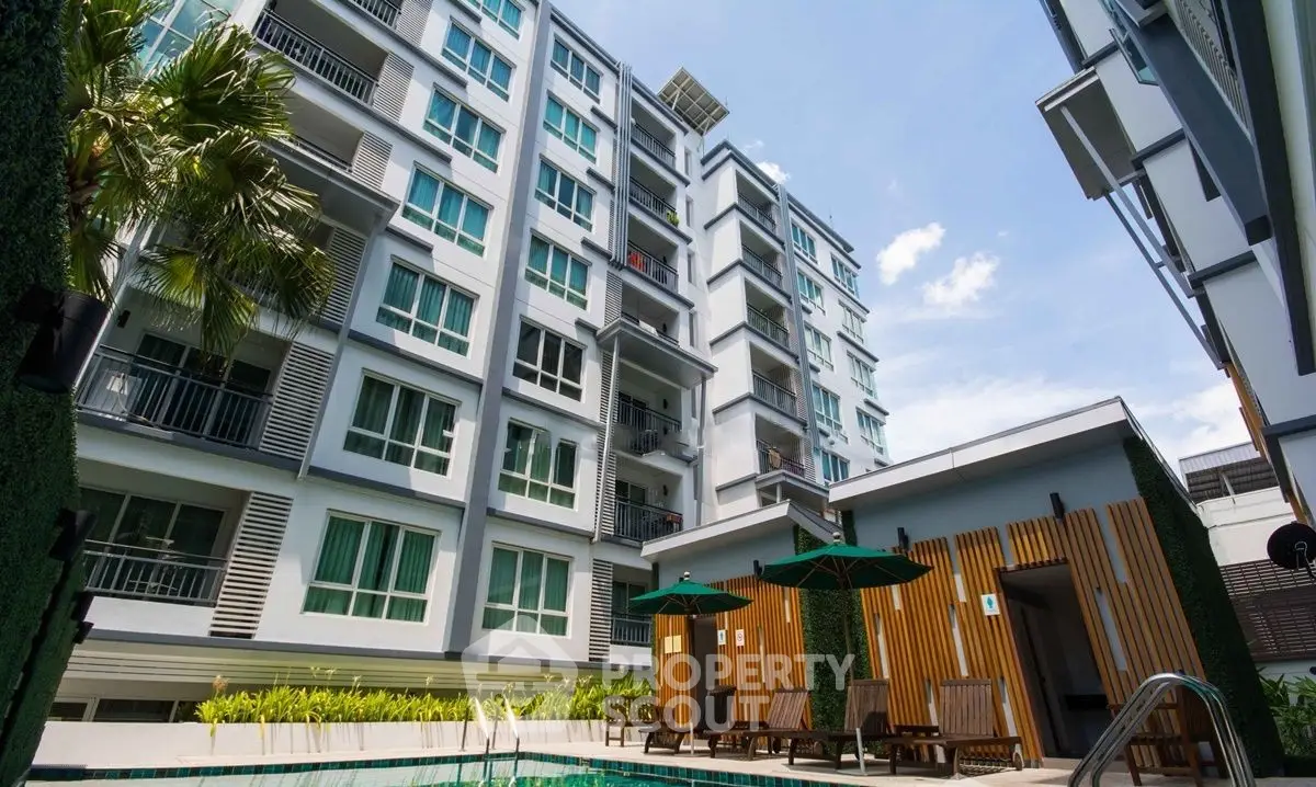 Modern apartment building with pool and sun loungers, perfect for urban living.