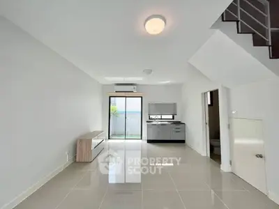 Modern open-plan living room with sleek kitchen and bright natural light.