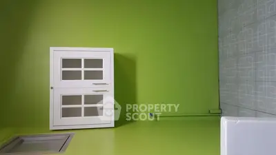 Modern kitchen with vibrant green walls and sleek white cabinets