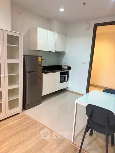 Modern kitchen with sleek cabinetry and stainless steel appliances in a cozy apartment setting.