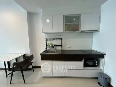 Modern kitchen with sleek cabinetry and compact dining area in a stylish apartment.