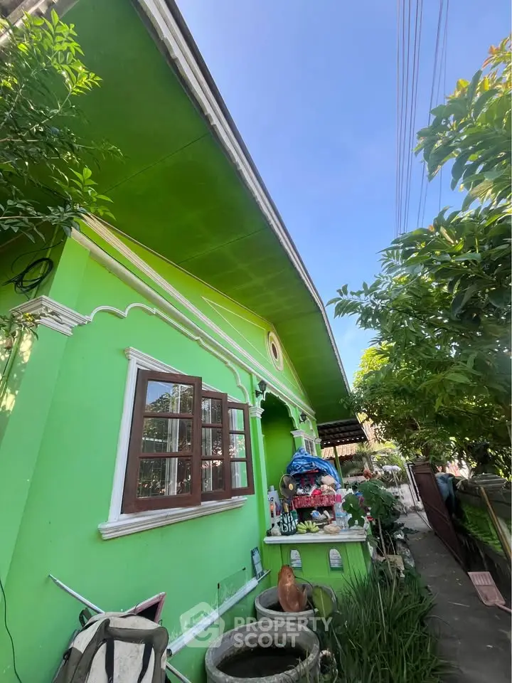 Charming green exterior house with lush garden and decorative elements, perfect for serene living.
