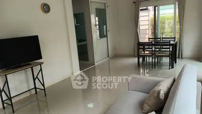 Spacious living room with modern decor and dining area, featuring large windows for natural light.