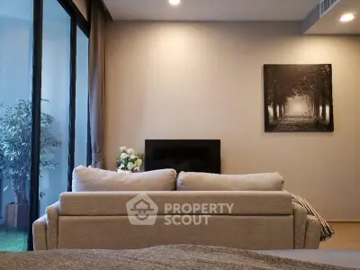 Modern living room with cozy sofa and elegant decor, featuring a large window and stylish artwork.