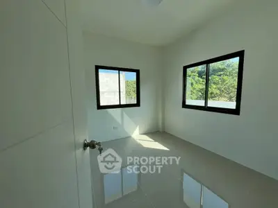 Bright and airy bedroom with large windows and glossy tiled floors, offering a serene view of greenery.